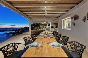 una sala da pranzo con un lungo tavolo in legno e sedie di Alia Villa Mykonos a Mykonos Città