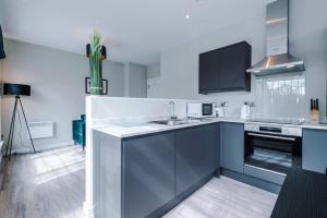 a white kitchen with a sink and a stove at Elysée Suites - Stylish 1 Bed Flat in Southport in Southport