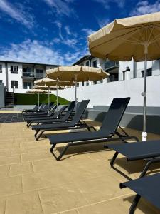 una fila di sedie a sdraio con ombrelloni su un patio di Casa Oti en Roque del Mar a Costa de Antigua