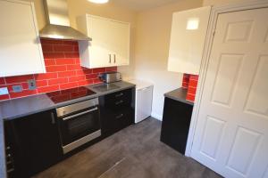 a small kitchen with white cabinets and a stove top oven at Pinegrove flat in Fort William
