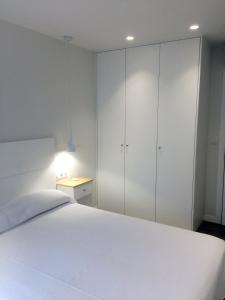 a bedroom with a white bed and white cabinets at Apartamentos Angelito Playa América B in Nigrán