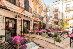 a patio with tables and chairs with pink umbrellas at LovelyLoft Santa Cruz in Alicante