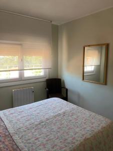 a bedroom with a bed and a mirror and a chair at Apartamentos Angelito Playa América Ático in Nigrán +2 photos