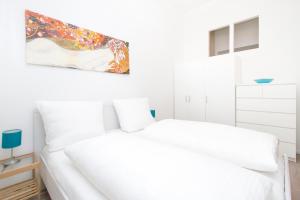 1 dormitorio con 2 camas blancas y una pintura en la pared en Apartment Uthman Berlin-Neukölln en Berlín