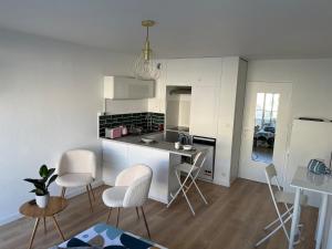 Una cocina con gabinetes blancos y una mesa y sillas. en Joli studio cozy, balcon, Cité des Congrès, Gare Sud, en Nantes 11 fotos más