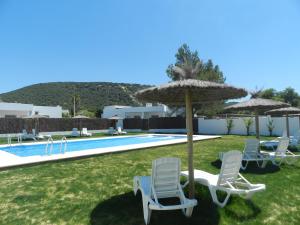 a group of chairs and an umbrella next to a swimming pool at DADA CAÑOS in Los Caños de Meca