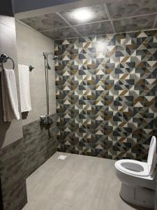 Un baño con inodoro y una pared de mosaico. en Solace Inn, en Islamabad