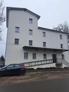 Czarny samochód zaparkowany przed białym budynkiem w obiekcie Stary Młyn w mieście Glinik