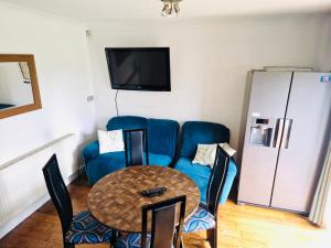 a living room with a blue couch and a table at Lovely 4 bed house with patio & bbq in Slades Green
