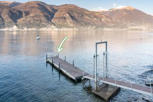a dock in the middle of a lake with mountains at Ninfea Apartments by Wonderful Italy in Lezzeno