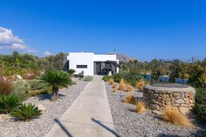 a garden with palm trees and a white building at Villa Galini in Haraki