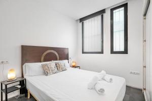 Un dormitorio blanco con una cama grande con toallas. en LovelyLoft Navíos, en Alicante
