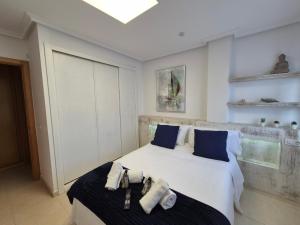 a bedroom with a large white bed with blue pillows at Apartamento Alborada de Llanes in Posada de Llanes +19 photos