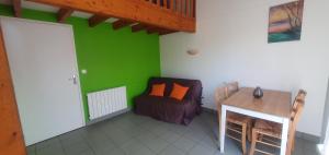 a room with a green wall with a couch and a table at Chalets Moulière Evasion in Montamisé