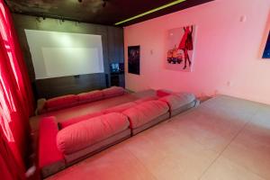ein Wohnzimmer mit einem roten Sofa und einem Bildschirm in der Unterkunft Casa Completa Condomínio Rosa Internacional - ao lado Sufland - Garopaba-SC in Garopaba + 26 Fotos
