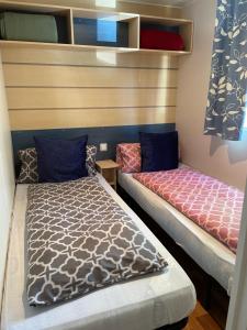 two beds in a small room with a bedskirts at Le mobilhome d 'Edit - C34- Proche Europa Park in Boofzheim