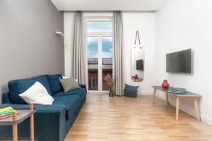 a living room with a blue couch and a television at Hotel Piazza Bellini & Apartments in Naples