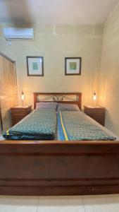 un letto in una camera con due comodini e due lampade di Pool and Fun in Gozo, Great place to relax and enjoy nature a Għajn il-Kbira