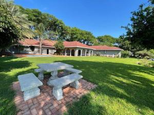 a picnic table and benches in a yard at Riecor Guest Farm in Thabazimbi