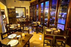 um restaurante com mesas e cadeiras de madeira e janelas em Estalagem Casa Grande Pousada em Ubatuba