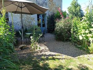 a garden with an umbrella and a table and chairs at joli gîte plain pied in Maférat