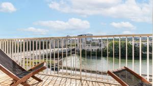 un balcon avec deux chaises et une vue sur l'eau dans l'établissement APPARTEMENT avec vue sur la Seine 10' en voiture de Paris et de la Tour Eiffel, à Boulogne-Billancourt