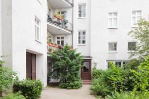 ein weißes Apartmenthaus mit einem Baum davor in der Unterkunft Apartment Uthman Berlin-Neukölln in Berlin