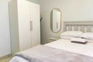 Un dormitorio con dos camas y un espejo. en Grace Villas 8, en East London