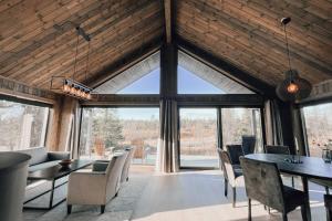 a living room with a table and chairs and windows at Modern Mountain Cabin - Outdoor Hot Tub - 8 Beds in Torpo