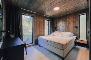 a bedroom with a bed in a room with windows at Modern Mountain Cabin - Outdoor Hot Tub - 8 Beds in Torpo