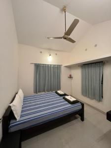 a bedroom with a bed and a ceiling fan at The Green Thumb Farm Stay in Mundakāyam