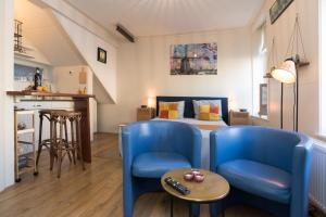 a bedroom with a bed and two blue chairs at Luttik Oudorp 30 in Alkmaar
