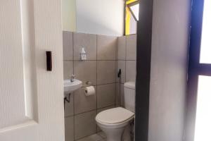 a small bathroom with a toilet and a sink at Grace Villas modern studio apartments in East London +23 photos