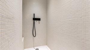 La salle de bains est pourvue d'une douche avec un tuyau et de carrelage blanc. dans l'établissement APPARTEMENT avec vue sur la Seine 10' en voiture de Paris et de la Tour Eiffel, à Boulogne-Billancourt