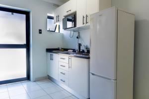 Una cocina con gabinetes blancos y un refrigerador. en Grace Villas 7, en East London 2 fotos más