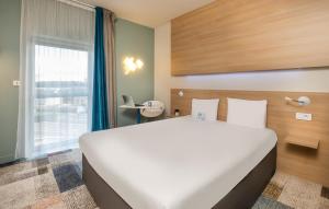 勒芒基里亚德东勒芒酒店的带窗户的房间里有一张白色的大床