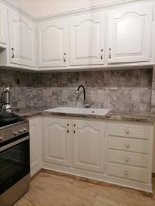 a kitchen with white cabinets and a sink at Απεριόριστη Θέα δίπλα στην πόλη in Ano Syros +13 photos