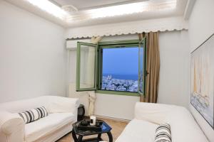 a living room with a white couch and a window at Απεριόριστη Θέα δίπλα στην πόλη in Ano Syros