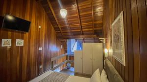 a bedroom with wooden walls and a television and a refrigerator at Pousada Caliandra Da Serra in Canela