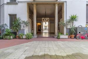 a building with columns and potted plants in a courtyard at Stradivarius House - Carozzi Apartments in Milan