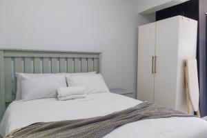 1 dormitorio con 1 cama blanca y armario blanco en Grace Villas 28, en East London