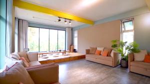 a living room with couches and a large window at Black Stone Family Garden Villa in Yaoqiaoyu +28 photos