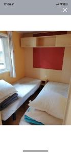 two twin beds in a room with a window at Camping Sable d'Or 3 chambres in Cap d'Agde +10 photos