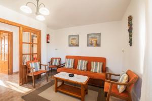 ein Wohnzimmer mit einem orangenen Sofa und Stühlen in der Unterkunft Casa vacacional El Angel in La Pesa
