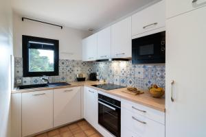 a white kitchen with white cabinets and a window at La Résidence du Bailli in Rayol-Canadel-sur-Mer