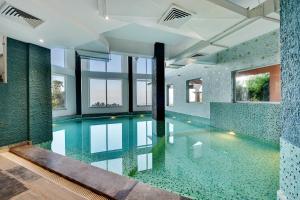 una piscina coperta con piastrelle verdi e finestre di Tiaraa Jujurana Resort & Spa a Dharamsala