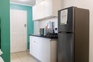 una cucina con frigorifero nero e armadietti bianchi di Modern apartments at CZ KUBS a East London Altre 7 foto