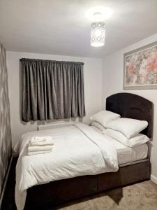 a bedroom with a bed with white sheets and a window at Entire 3 bedroom luxurious house, Wigan , Manchester in Wigan