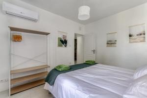 a white bedroom with a bed and a sliding glass door at Le Bambou Wifi Proche des pontons et du Doul in Peyriac-de-Mer