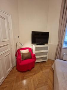 sala de estar con silla roja y TV de pantalla plana en M Apartments - Downtown, en Budapest